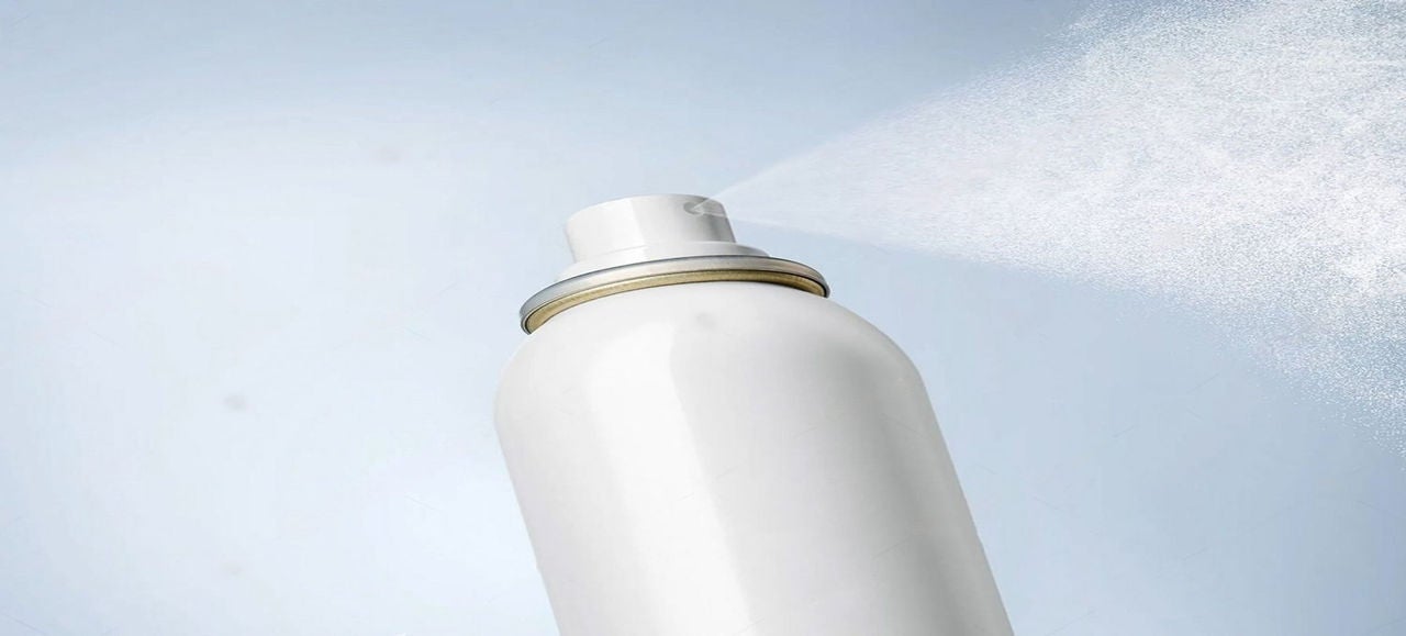 Gros plan sur un aérosol de déodorant blanc en train de pulvériser, illustrant la question du tri des emballages d’aérosols