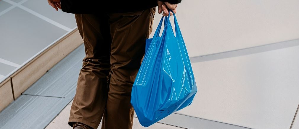 Sac poubelle Handybag bleu tenu par une main d’homme sur fond urbain