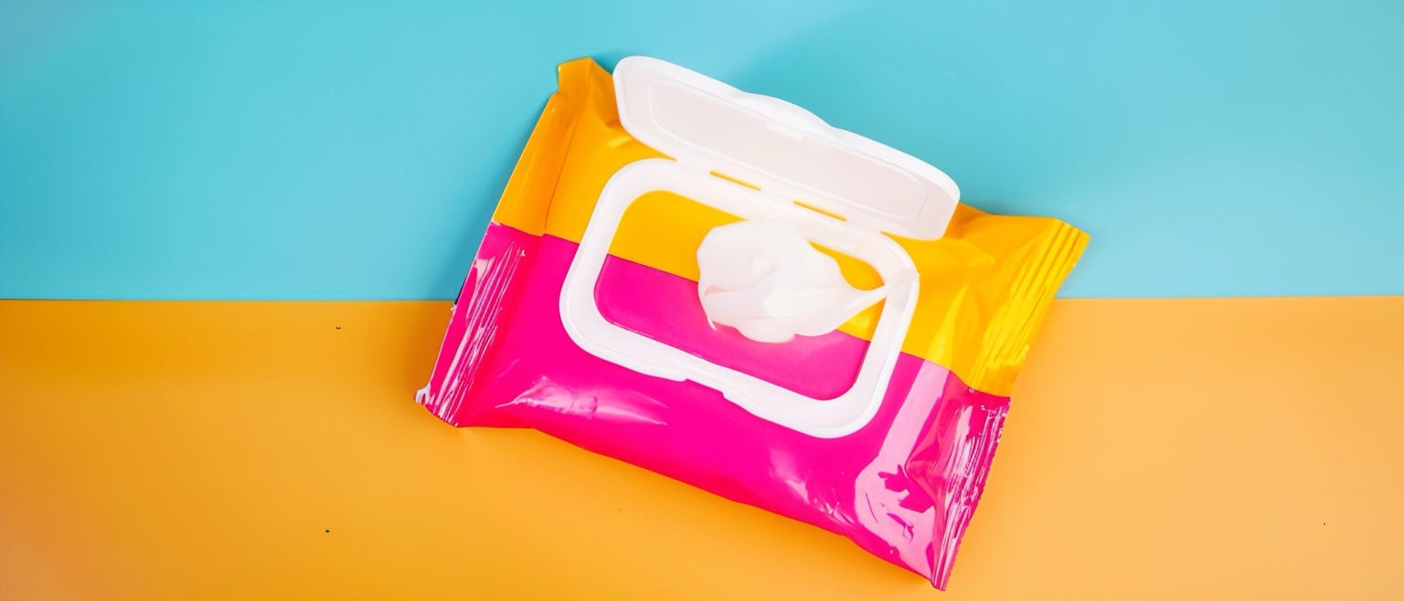 Paquet de lingettes humides coloré posé sur fond jaune et bleu