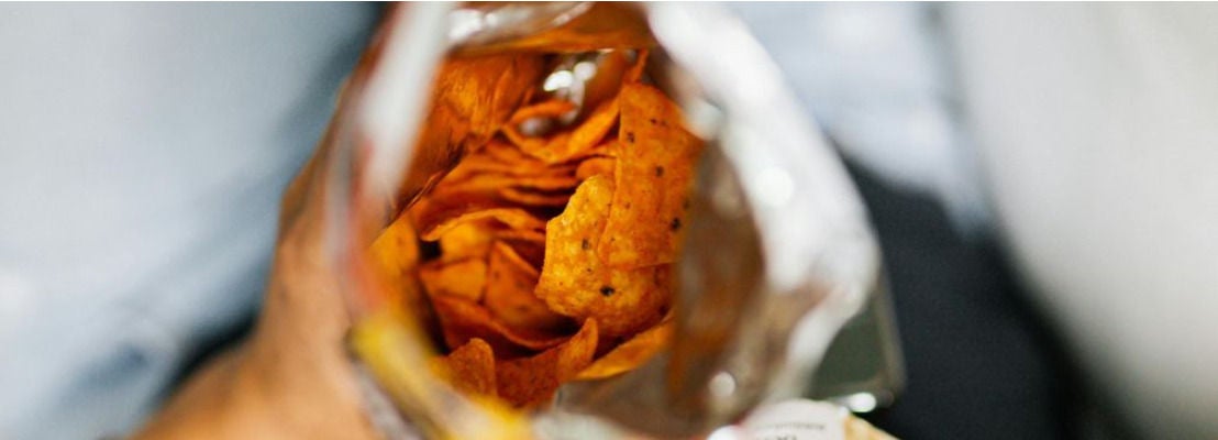 Paquet de chips ouvert tenu a la main sur un livre