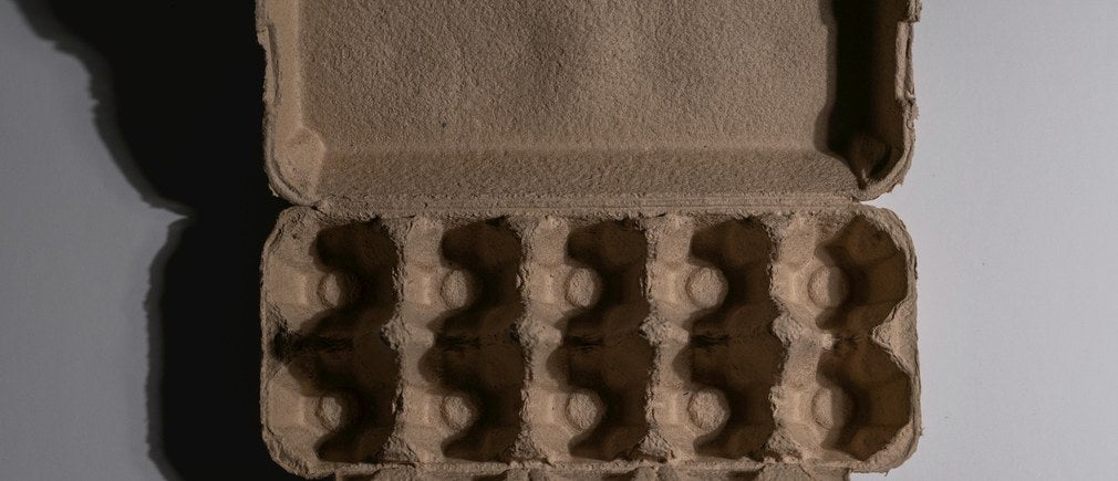 Boîte à œufs en carton vide ouverte vue de dessus sur fond gris