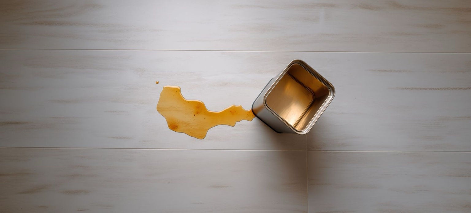 Conteneur métallique Handybag ouvert avec liquide éclaboussé sur surface en bois