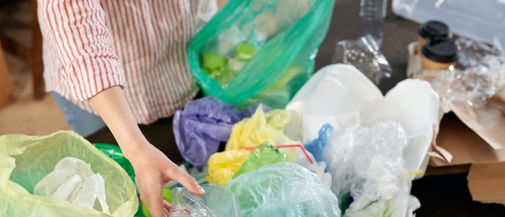 Personne triant des plastiques dans un sac poubelle Handybag vert