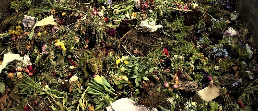 Un tas de déchets végétaux et de fleurs fanées dans un composteur en bois