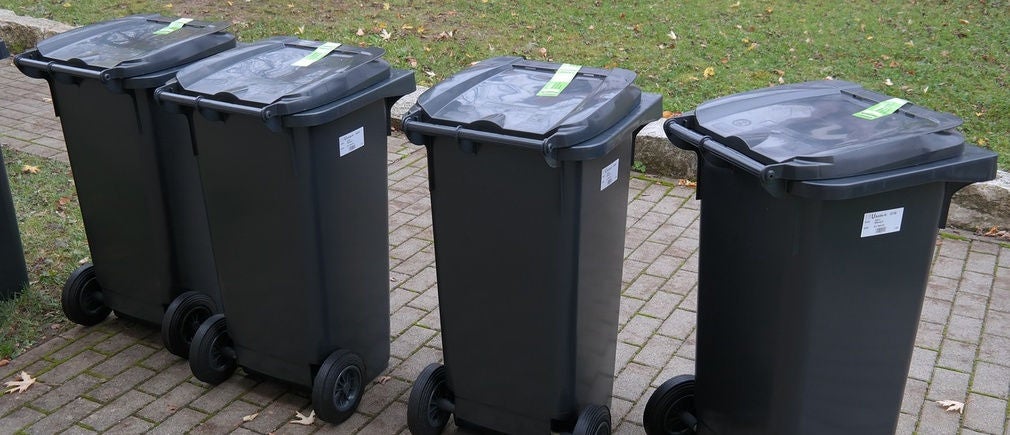 Une rangée de poubelles roulantes noires Handybag alignées sur un trottoir