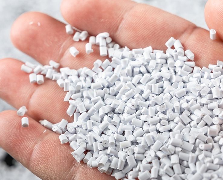 Une main tient des granules plastiques blanches