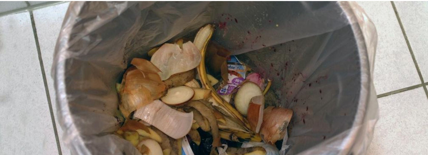 Une poubelle de cuisine remplie de déchets organiques, principalement des épluchures de légumes et de fruits, illustrant le tri des biodéchets ménagers au quotidien