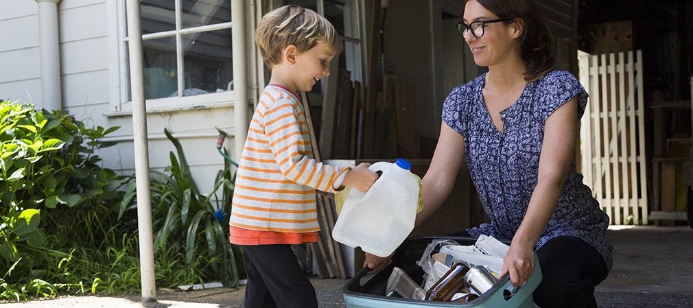 Mère et enfant triant des déchets plastiques et en carton avec un sac poubelle Handybag