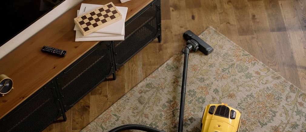Un aspirateur cylindrique est posé sur un tapis de salon moderne