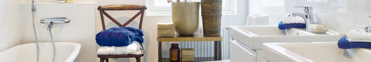 Salle de bain moderne avec double vasque, serviettes pliées sur une chaise et plantes décoratives