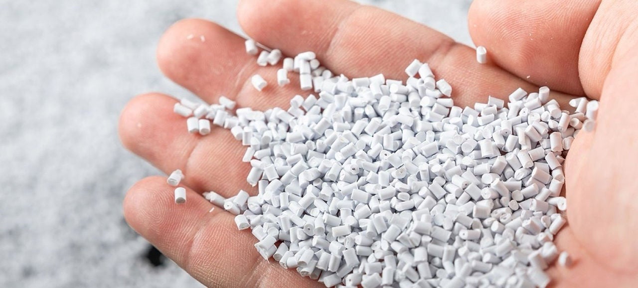 Une main tient des granules plastiques blanches