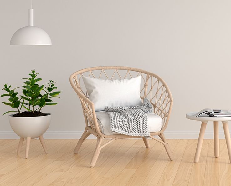 Chaise en osier avec coussin blanc et livre sur table basse à côté d’une plante