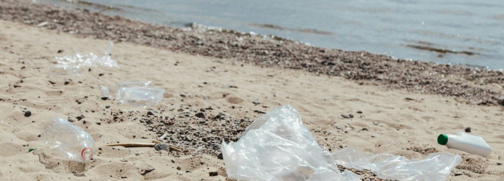 Dechets plastiques et boulleites eparpilles sur une plage de sable