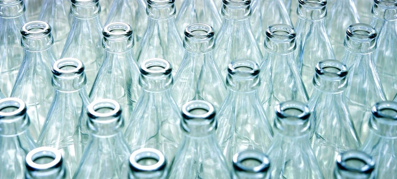 Bouteilles en verre transparentes rangées sur un fond clair