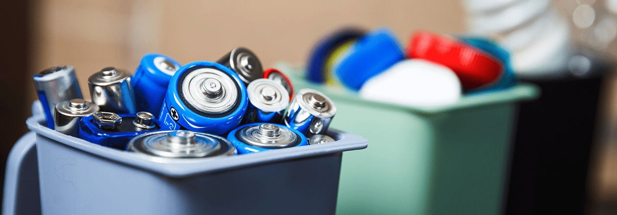 Un bac de collecte contient de nombreuses piles usagées destinées au recyclage, illustrant l’importance du tri des déchets dangereux pour l’environnement