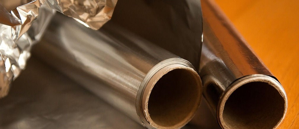 Deux rouleaux de papier aluminium partiellement déroulés posés sur une table en bois claire