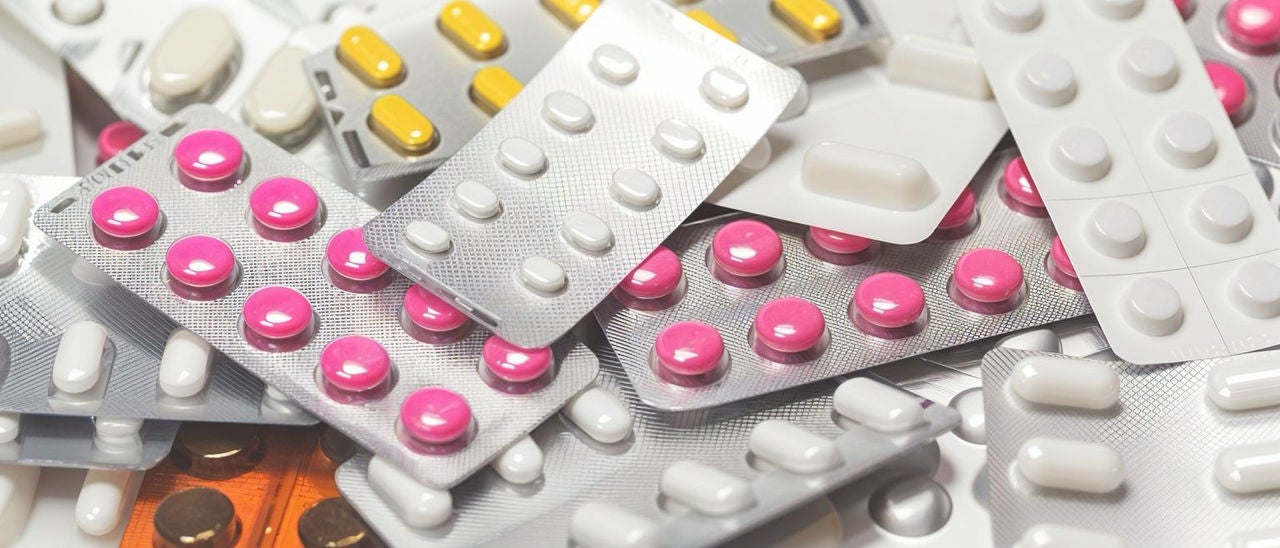 Plusieurs blisters de pilules mélangées sur fond blanc