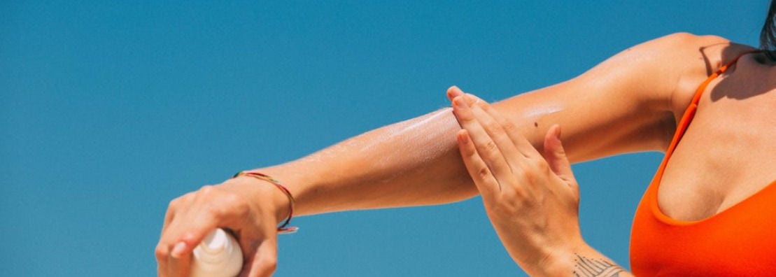 Femme appliquant de la creme solaire sur son bras